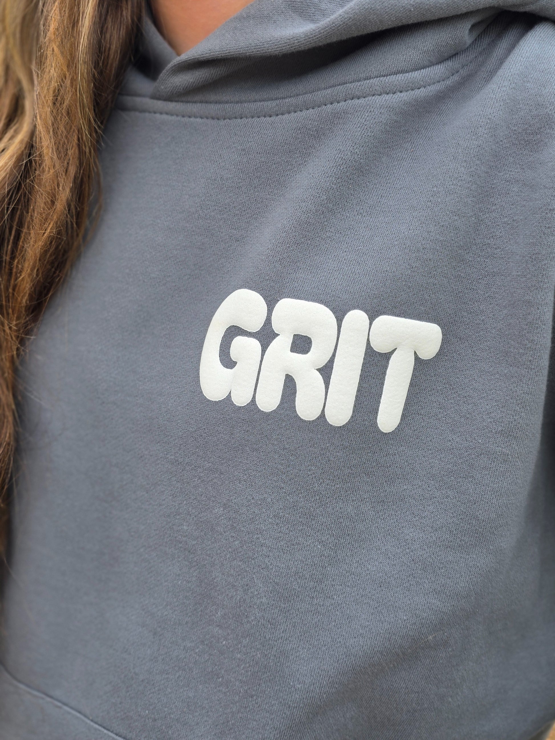 Gray hoodie with 'GRIT' text on a person wearing it