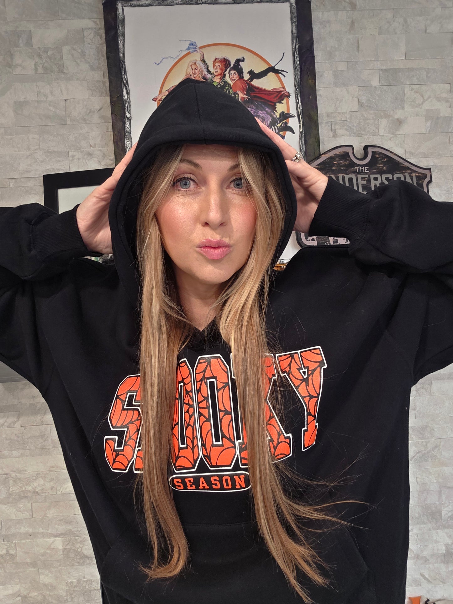 Person wearing a black hoodie with 'Spooky' text,