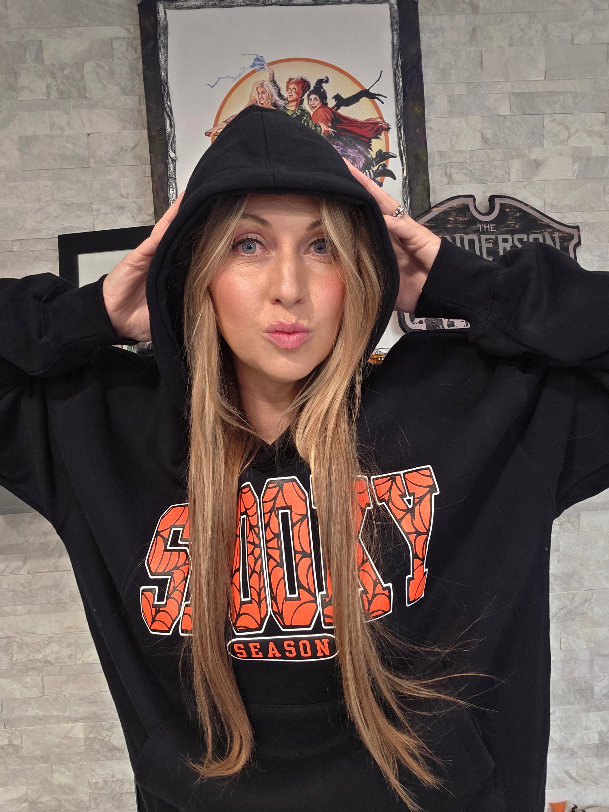 Person wearing a black hoodie with 'Spooky' text,