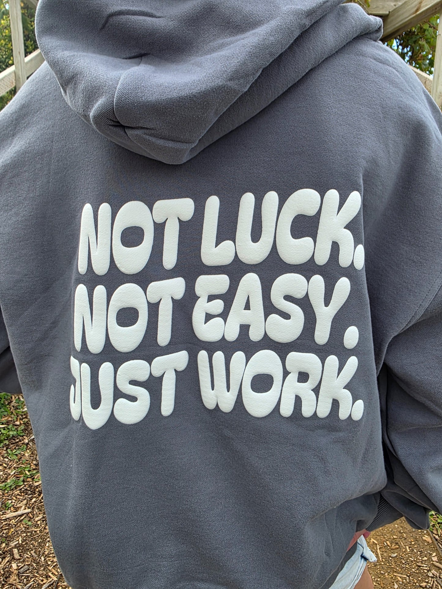 Gray hoodie with motivational text on the back, worn by a person outdoors.