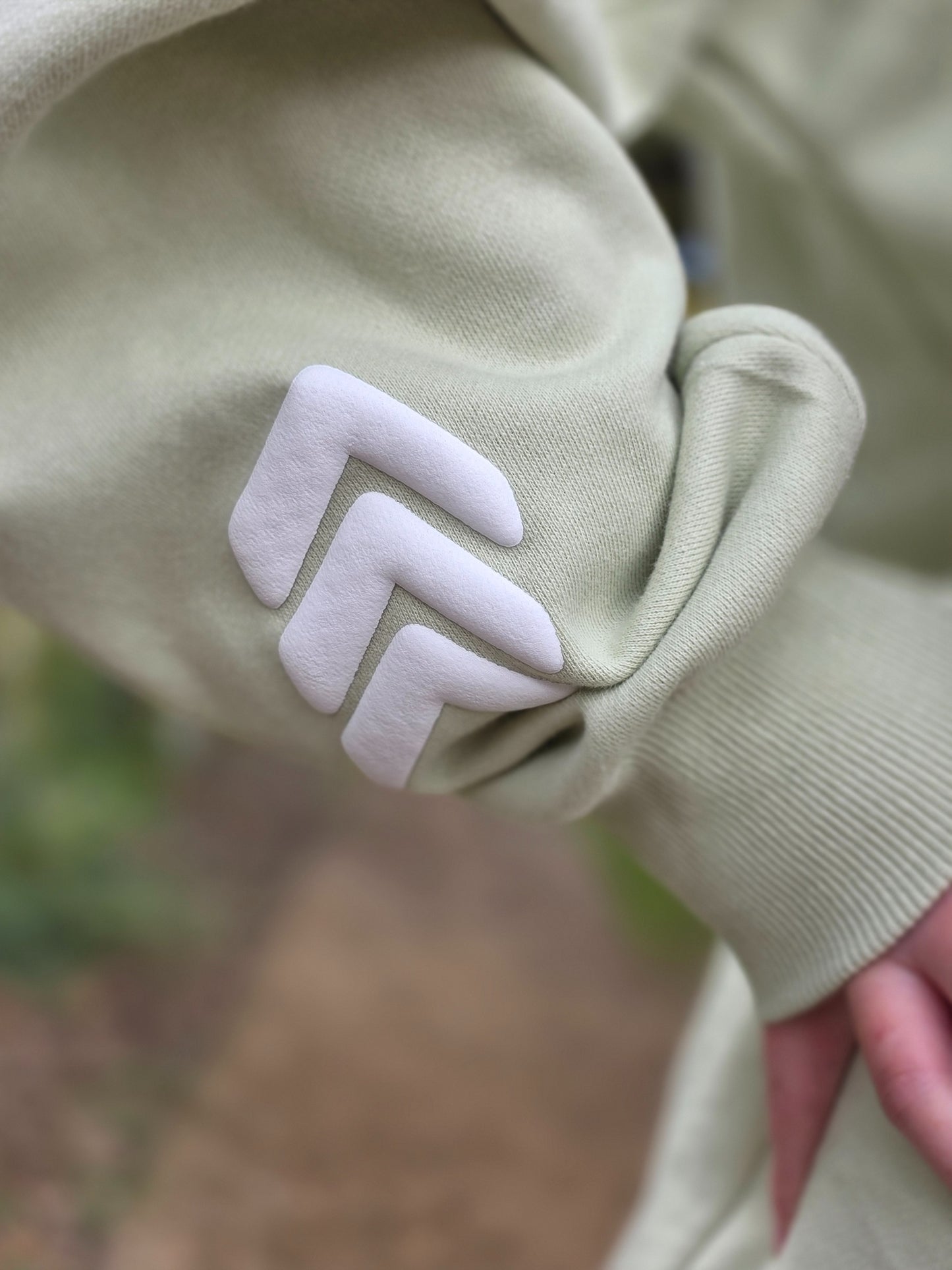 Close-up of a light green garment with a white zigzag pattern on a blurred natural background