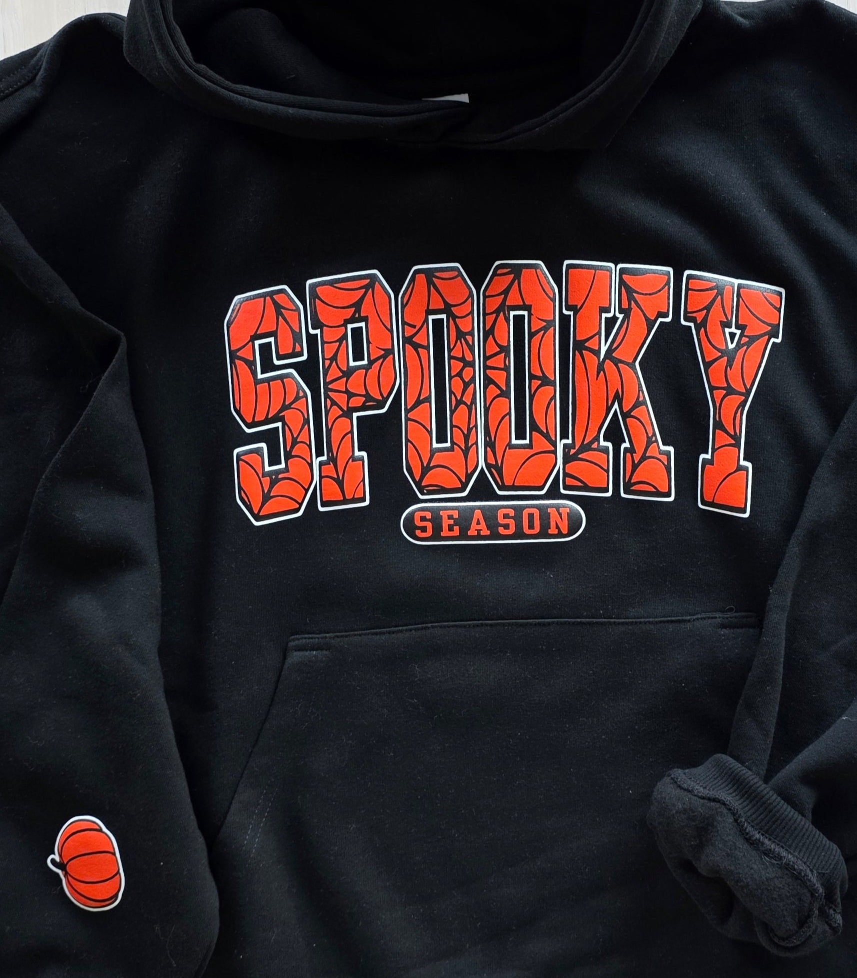 Black hoodie with 'Spooky Season' text in orange and Black with white outline on black hoodie