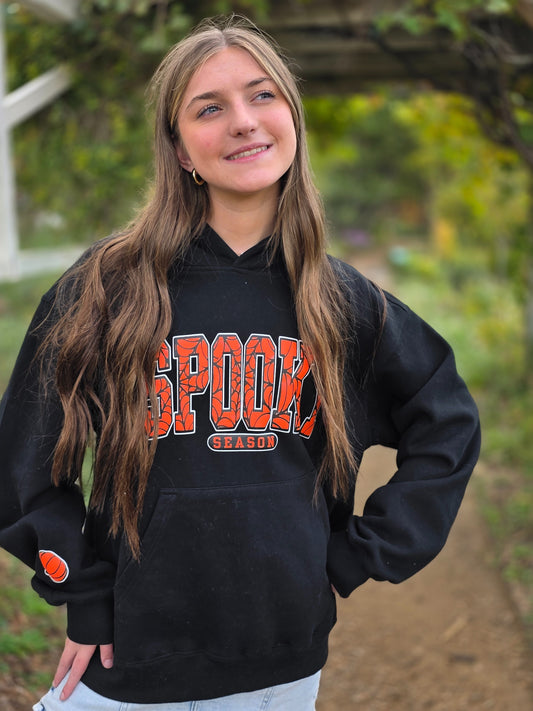 Person wearing a black hoodie with orange text outdoors