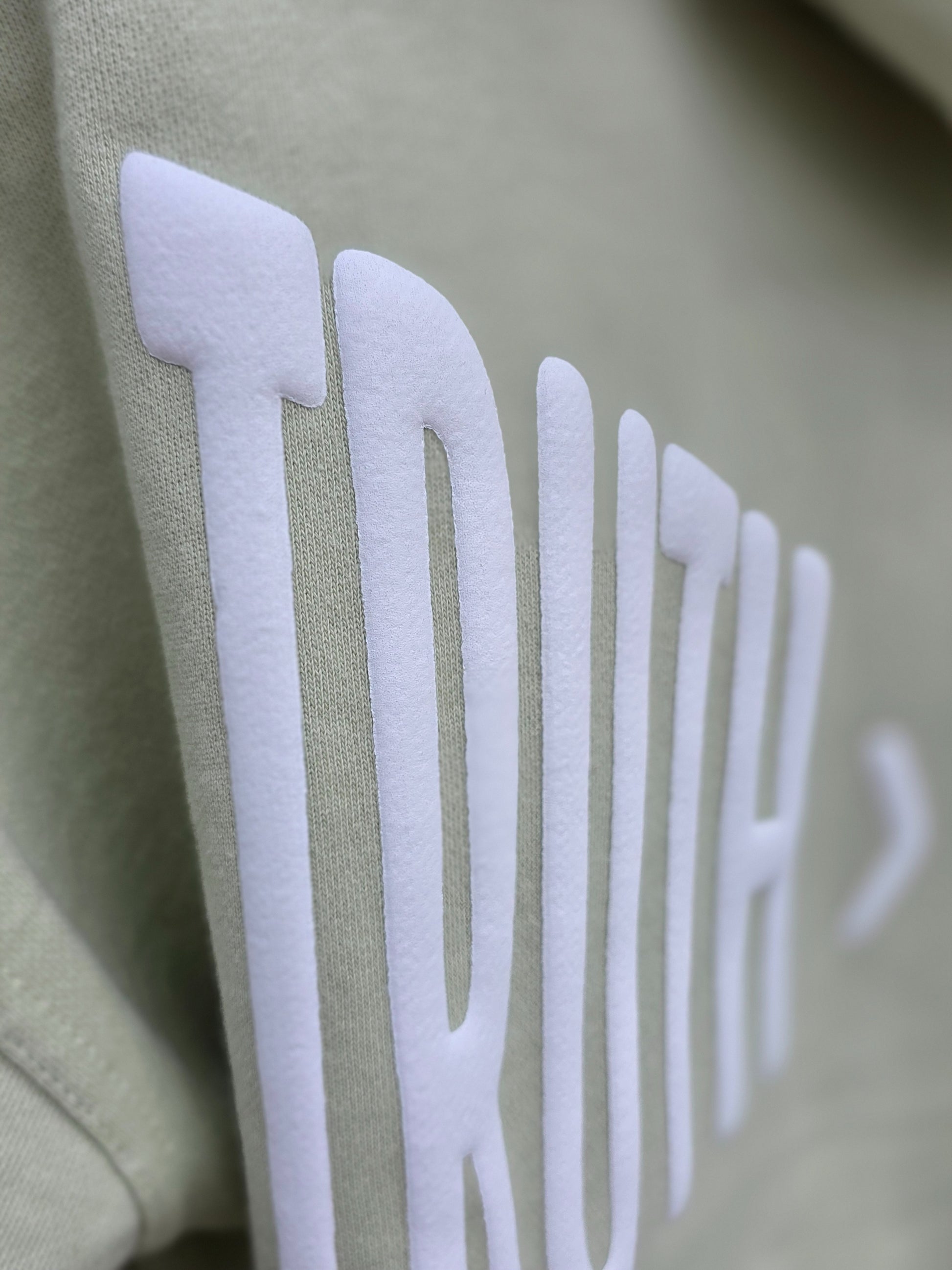 Close-up of a green hoodie with 'TRUTH' printed in white.