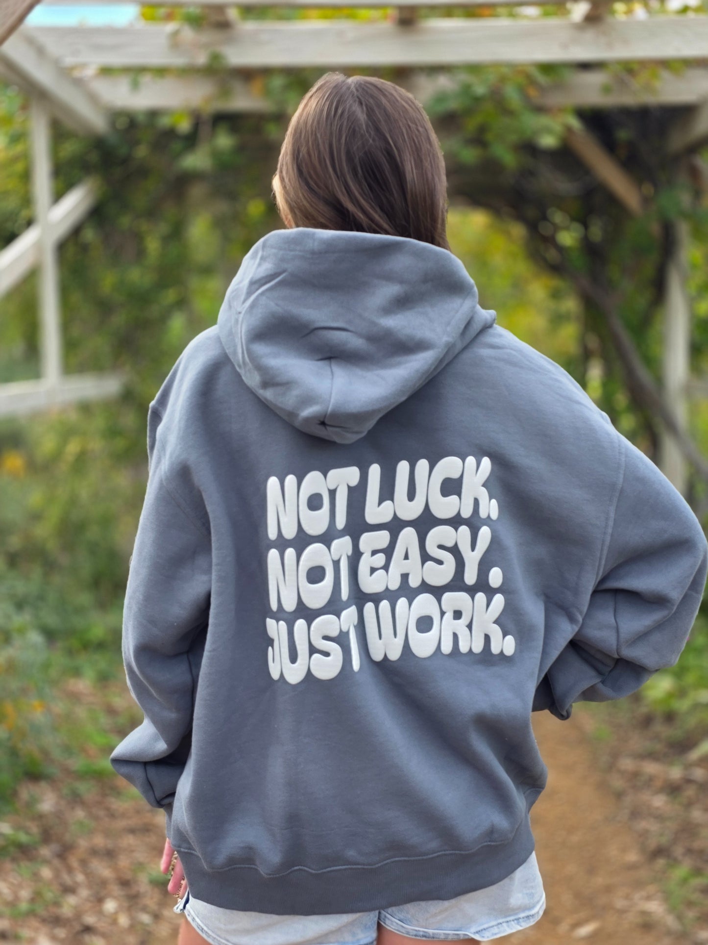 Person wearing a gray hoodie with motivational text outdoors