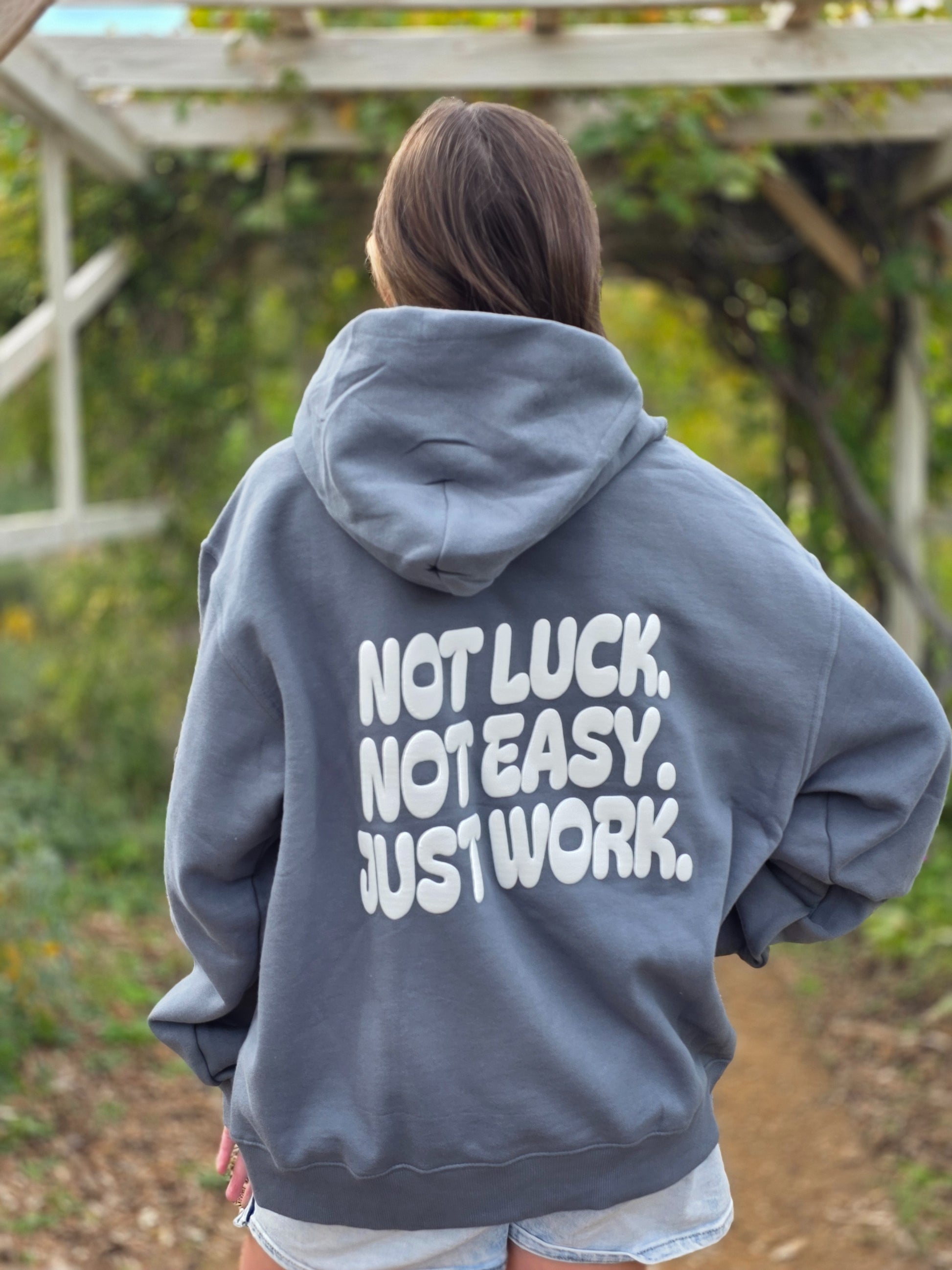 Person wearing a gray hoodie with motivational text outdoors