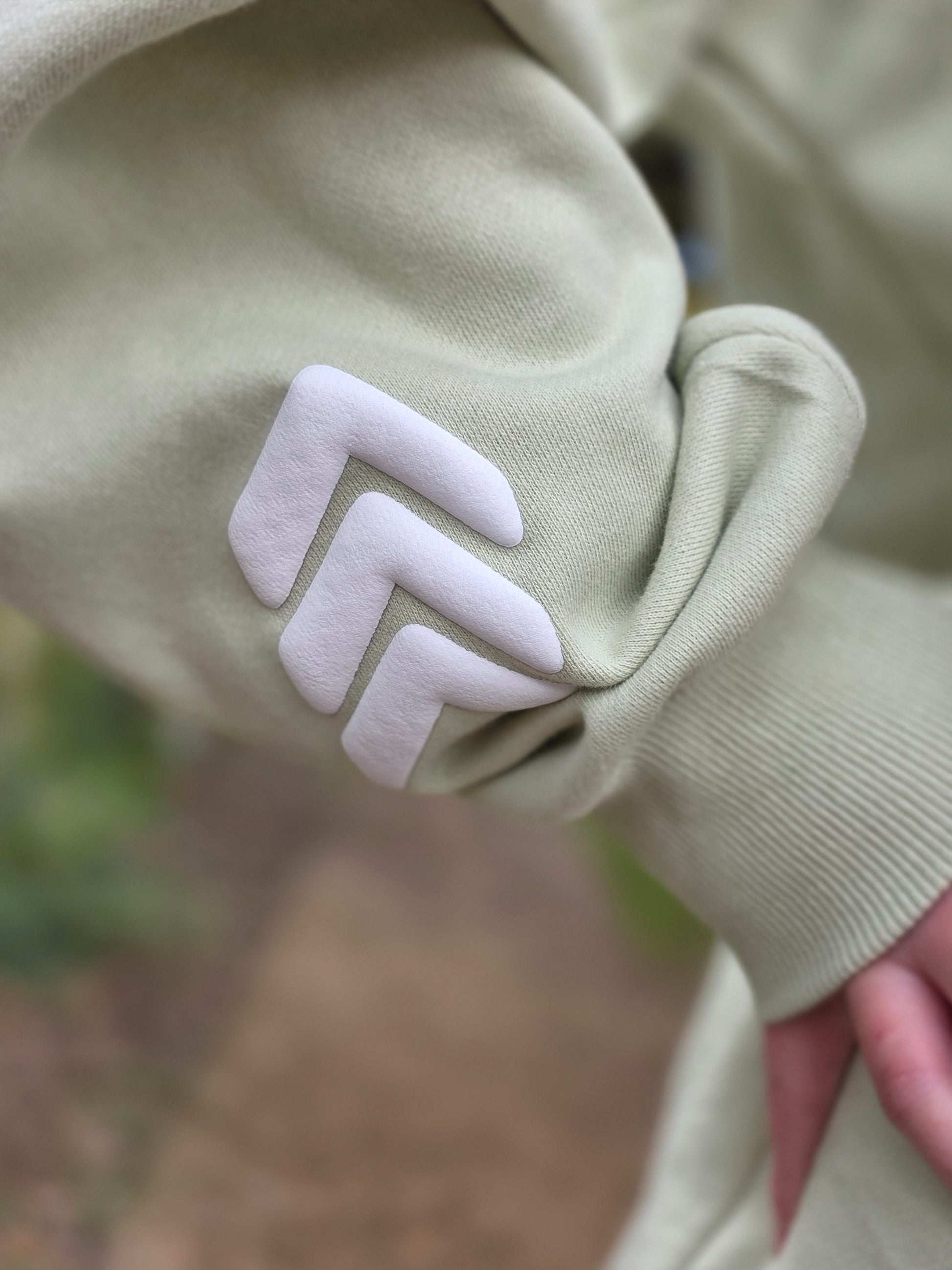 Close-up of a light green garment with a white zigzag pattern on a blurred natural background