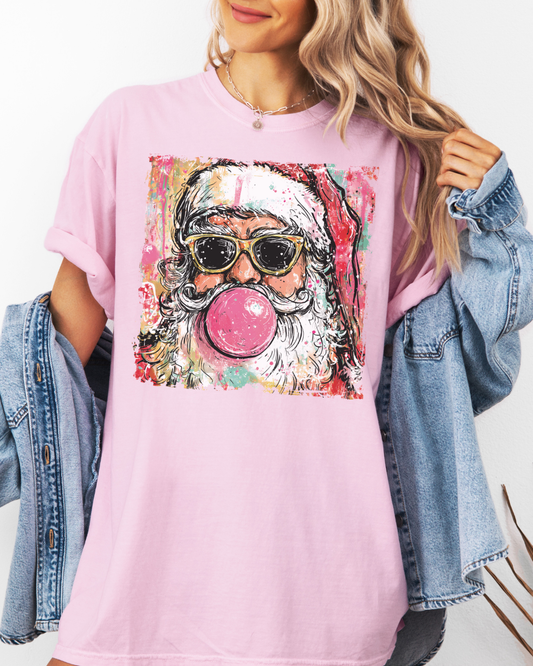 Person wearing a pink t-shirt with a colorful Santa Claus graphic, including sunglasses and bubble gum.